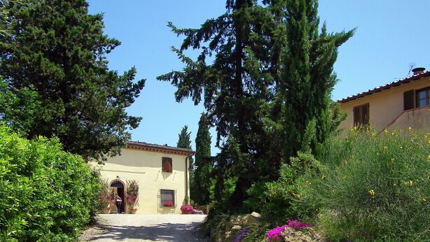 A rustic building with a gravel path leading to the entrance, surrounded by greenery and flowering plants. - Casa alle Vacche by Interhome (San Gimignano)
