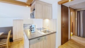 A compact kitchen with wooden cabinets, a built-in microwave, and a coffee maker. - Alpenblick by Interhome (Sölden)
