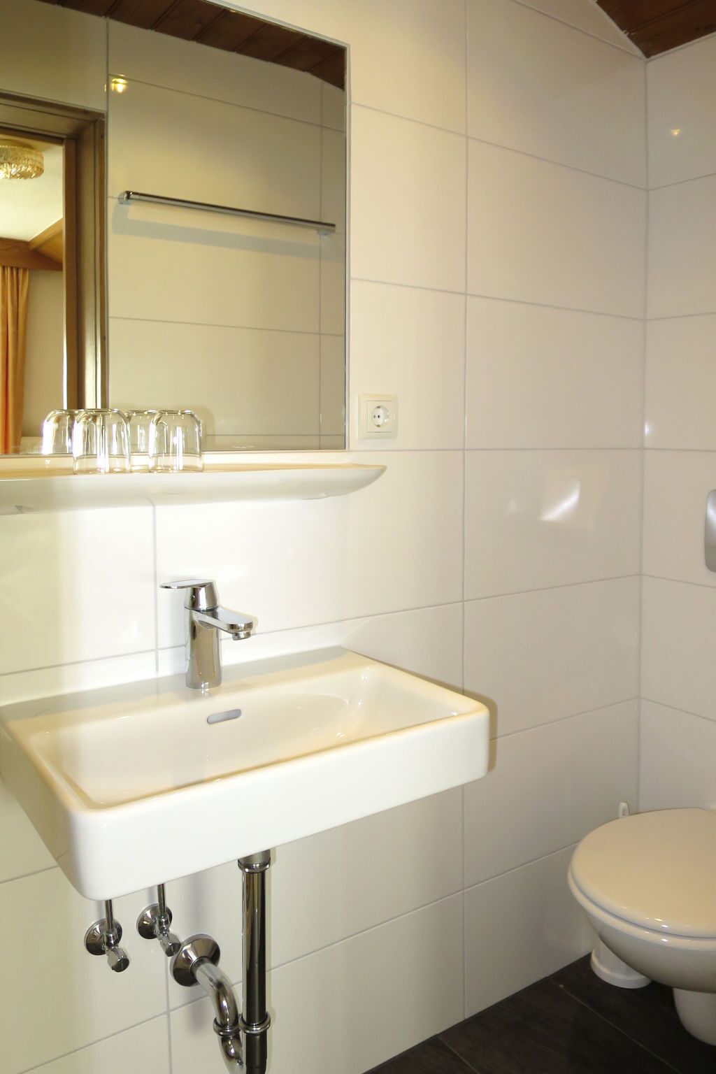 Une salle de bain avec un lavabo blanc, un miroir et des toilettes.