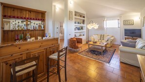Un grand espace de vie comprenant un bar en bois, un canapé, une table basse et un téléviseur.