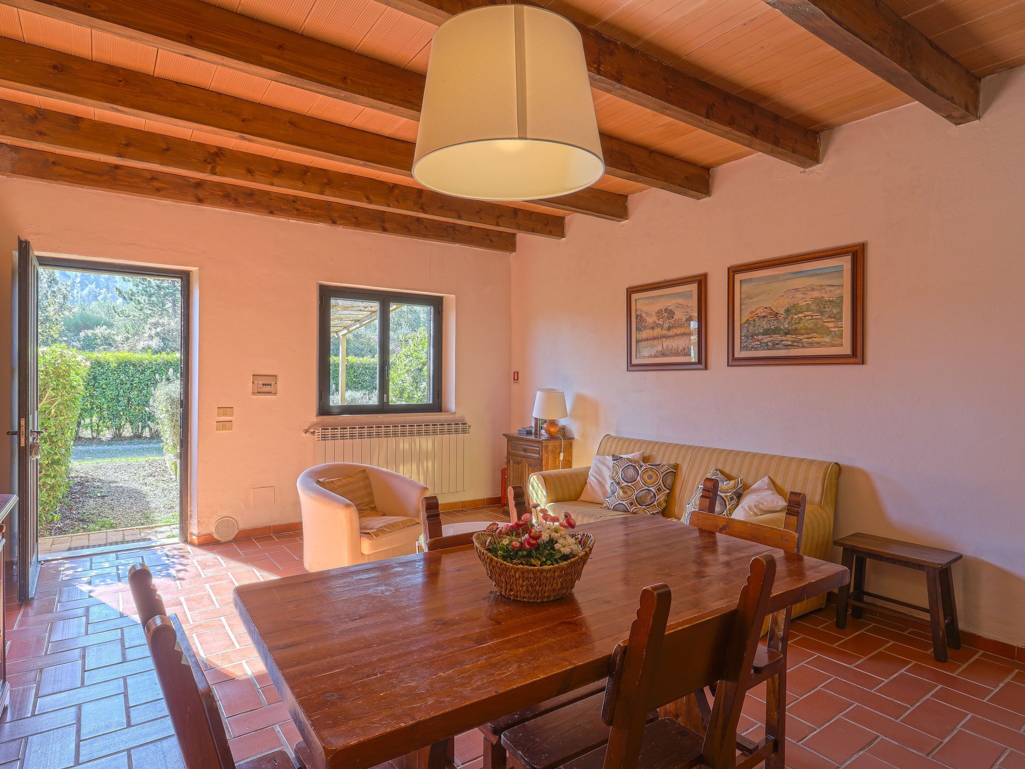 Uma área de jantar acolhedora com uma mesa de madeira, cadeiras, um banco e um lustre.