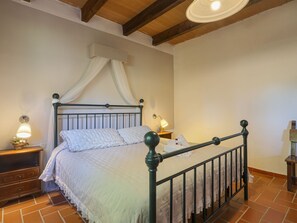 Une chambre à coucher avec un lit, des tables de chevet, une lampe et un ventilateur de plafond.