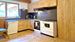 Eine kleine Küche mit Holzausbau, einem eingebauten Backofen und einem Fenster für natürliches Licht.