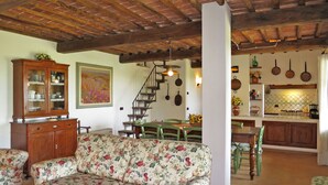 Una sala acogedora con un sofá floral, un mueble de madera y una escalera que sube a otro nivel.