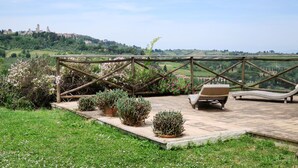 Un patio con cerco de madera, plantas en macetas y una silla de descanso.