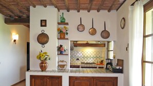 Una cocina con armarios de madera, salpicadero azulejado y ollas colgantes.
