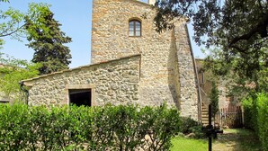 Un edificio de piedra con una pequeña ventana y un portal abierto, rodeado de follaje.