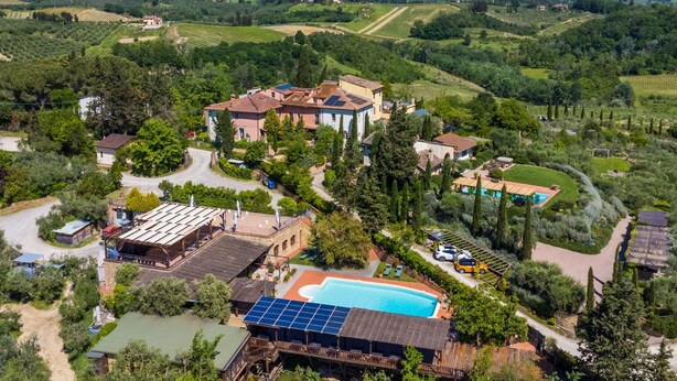 Una vila espaiosa amb piscina, panells solars i un viñedo al fons.
