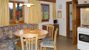 Tunnelmallinen keittiö, jossa on puinen ruokapöytä, tuolit ja sisäänrakennettu uuni.