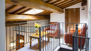 Ein geräumiges Loft mit freiliegenden Holzbalken, einem Oberlicht, einem Holztisch mit einer Vase und Ledersofas.