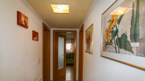 A hallway with a radiator, framed artwork, and a door leading to another room.