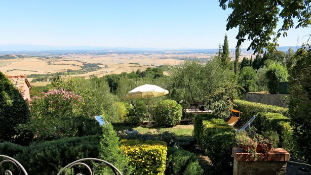 A garden with a view of distant fields, a white umbrella, and neatly trimmed hedges. - Castagni II (OCT101) by Interhome (Orciatico)