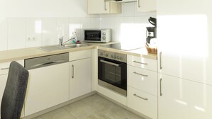 Una cucina moderna con mobili bianchi, lavastoviglie, forno, microonde e macchina per il caffè.