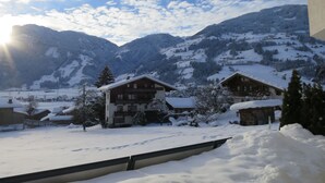 Paesaggio montano innevato con un chalet in legno e un edificio con balconi.
