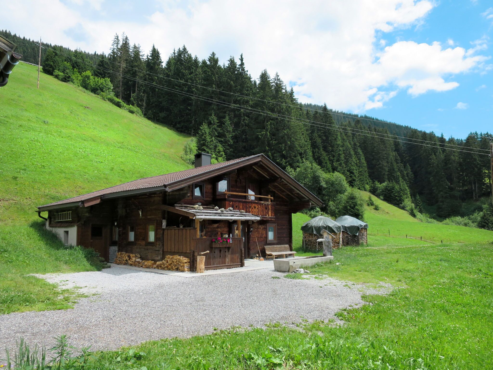 Eine rustikale Holzchalet mit Balkon, Kamin aus Stein und einem Schotterweg.