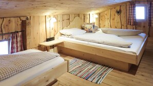 Ein Schlafzimmer einer Holzhütte mit zwei Betten, einem Nachttisch, einer Lampe und einem Fenster mit Vorhängen.