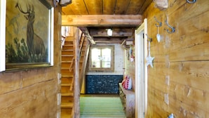 Ein Holzinnenraum mit einer Treppe, die zu einem Raum mit einem Fenster führt, einer Bank mit Kissen und einer an der Wand befestigten Meerstern-Dekoration.
