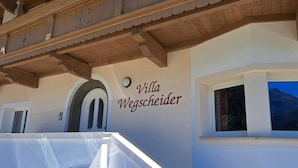 Un bâtiment sur lequel on peut lire l’inscription « Villa Wegscheider », et une fenêtre donnant sur la montagne.