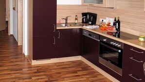 Une cuisine moderne avec des meubles de couleur sombre, un plan de travail en bois, un four encastré et une hotte en acier inoxydable.
