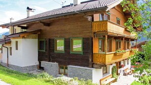 Un chalet en bois doté d’un balcon, de fondations en pierre et de nombreuses fenêtres.