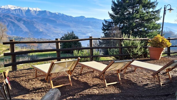 A wooden deck with four lounge chairs facing a scenic mountain view. - Le Bore (CNG122) by Interhome (Castelnuovo di Garfagnana)