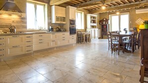 A spacious kitchen with a large island, wooden beams on the ceiling, and ample natural light from windows.