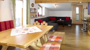 A cozy living room with a wooden dining table, a sofa, and a bar area. - Apart Vorwies by Interhome (Fügen)