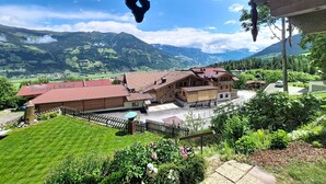 A mountain view with a house, a wooden fence, and a clear sky.