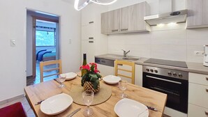 A modern kitchen with a dining area, stainless steel appliances, and a view through the door.