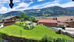 A residential area with houses, a well-maintained lawn, and mountains in the background.