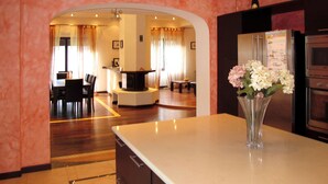 A modern kitchen with a central island, a dining area with a curved bench, and a living room with a fireplace. - Natalie (BLU170) by Interhome (Bagni di Lucca)