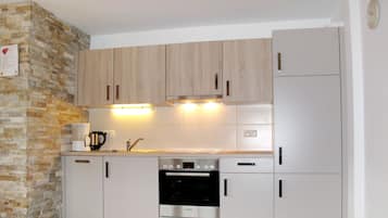 A compact kitchen with wooden cabinets, a Bosch oven, and a built-in refrigerator.