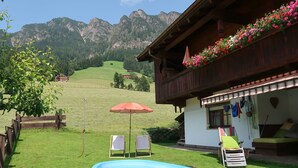 A pool in a backyard with a mountain view, a wooden house with flower boxes, and a small garden area. - Theresia by Interhome (Alpbach)