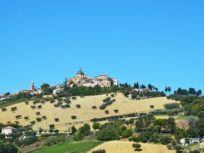 A hillside town with a prominent church featuring a dome and bell tower, surrounded by olive groves and residential buildings. - Serrani by Interhome (Roseto degli Abruzzi)