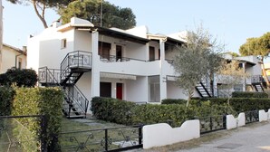 Un edifici residencial de dues plantes amb un balcó, una escala i una porta vermella.