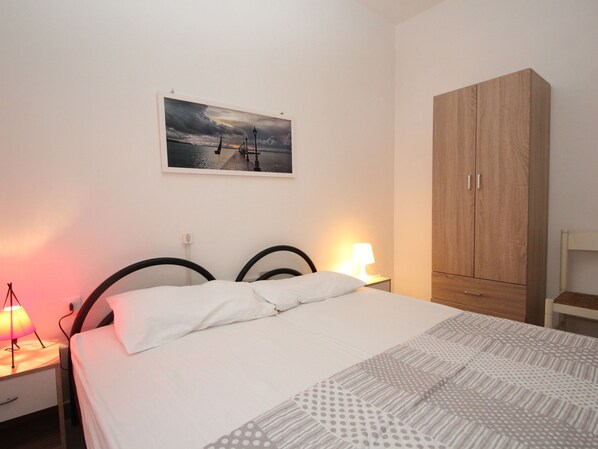 A bedroom with a bed, a nightstand with a lamp, a wardrobe, and a framed picture on the wall. - Villa Fausta by Interhome (Rosolina Mare)