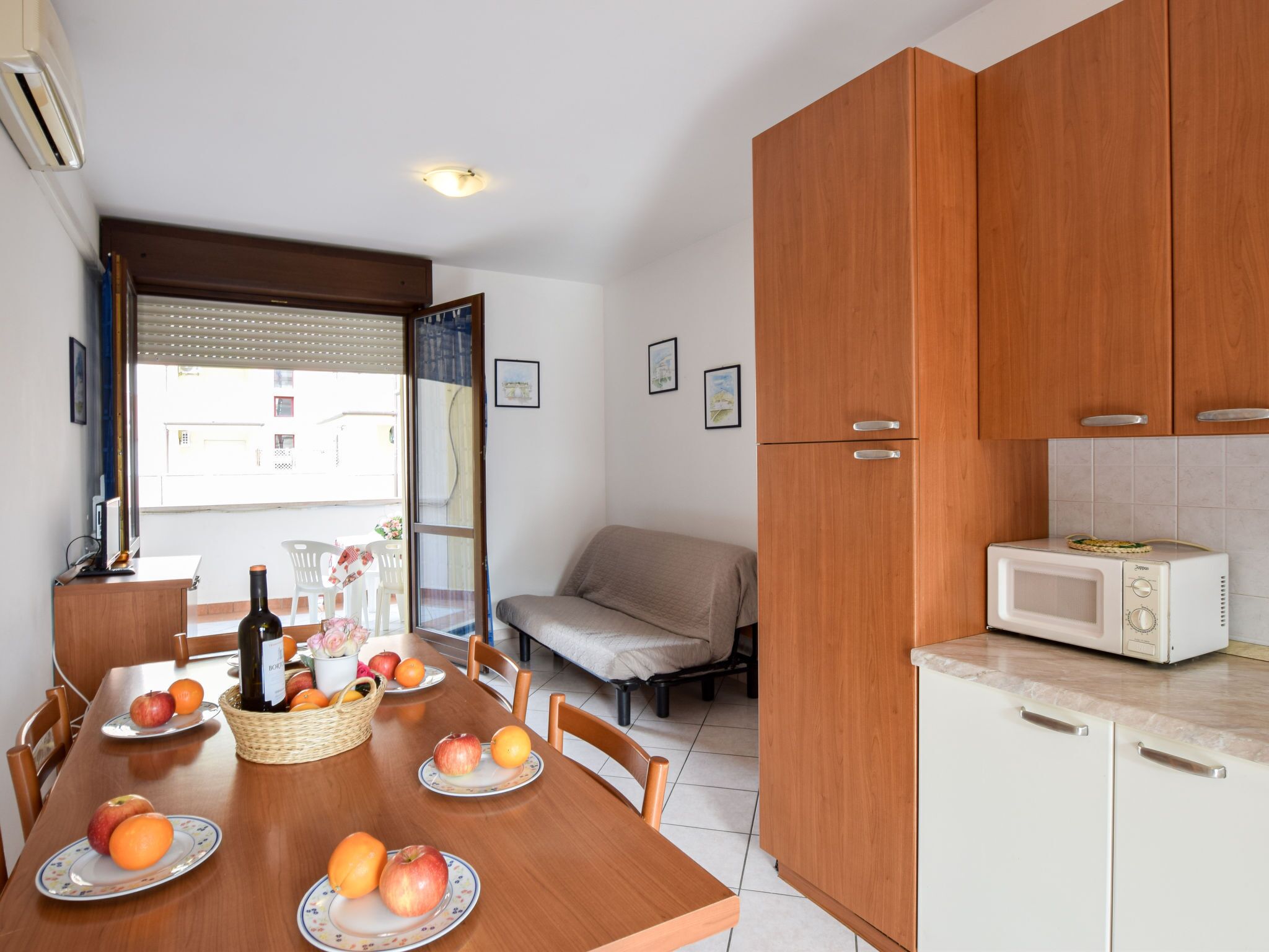 A compact kitchen with a microwave, wooden cabinets, and a dining area with a table set for a meal.