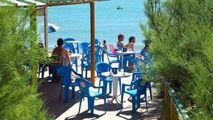 Un espace extérieur aménagé avec des chaises et des tables en plastique bleu, donnant sur une étendue d’eau.