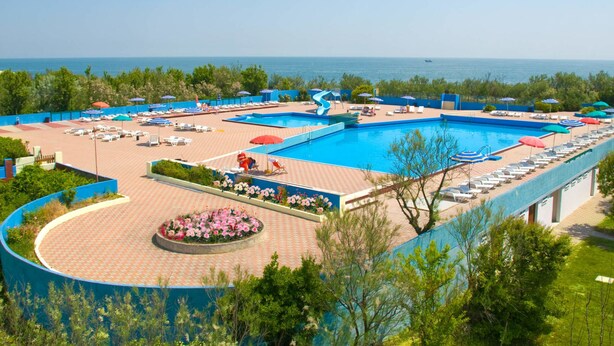 Un complexe hôtelier doté d’une grande piscine, de chaises longues et offrant une vue sur la mer.