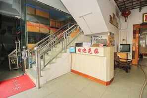 A reception desk with a staircase, a television, and a red carpet. - Qionghai Boyi Fanjiale Hotel (Qionghai)