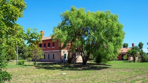 A building with a brick facade, multiple windows, and a large tree in front. - Ca' Del Pioppo by Interhome (Cavallino)