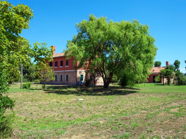 Ein Gebäude mit Ziegelverkleidung, zahlreichen Fenstern und einem großen Baum davor.