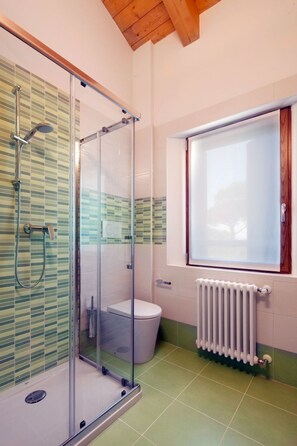 Ein modernes Badezimmer mit einer ein Glasfachwerk-Duschkabine, einer Toilette und einem Fenster mit Blick.