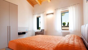 A bedroom with a large bed, a desk, and two windows. - Ca' Del Pioppo by Interhome (Cavallino)