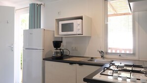 A compact kitchen with a microwave, coffee maker, and gas stove.