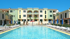 Una piscina amb gandules i ombrel·les, envoltada d'edificis d'àmples balconades.