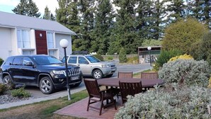 A residential area with a house, a parked SUV, and a table with chairs.