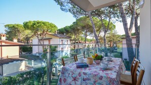 A balcony with a table set for dining, overlooking a residential area with trees and houses. - Elisabeth by Interhome (Lignano Pineta)