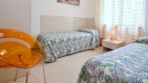 A bedroom with two beds, a nightstand, a chair, and a painting on the wall. - Villa Rosanna by Interhome (Lignano Pineta)