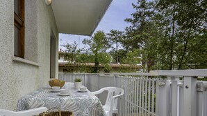 A balcony with a table set for dining, white chairs, and a white railing. - Villa Rosanna by Interhome (Lignano Pineta)